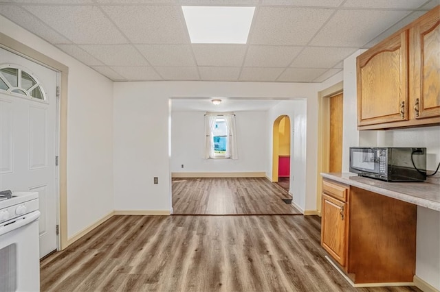 kitchen featuring white range oven, hardwood / wood-style flooring, and a drop ceiling