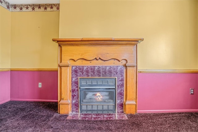 interior details with a tiled fireplace and carpet flooring