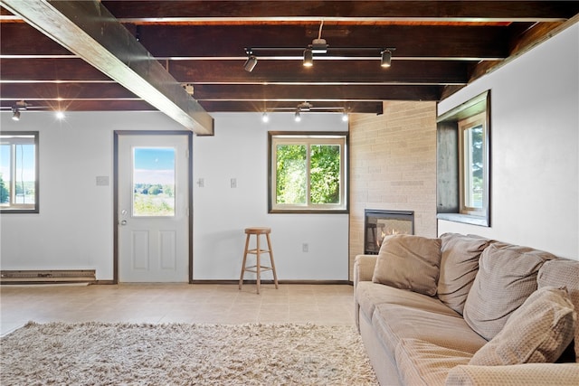 unfurnished living room featuring beamed ceiling, a fireplace, a baseboard radiator, rail lighting, and ceiling fan