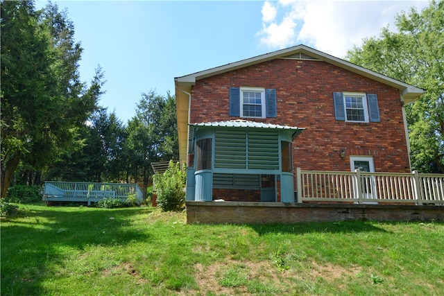 rear view of house featuring a wooden deck and a lawn