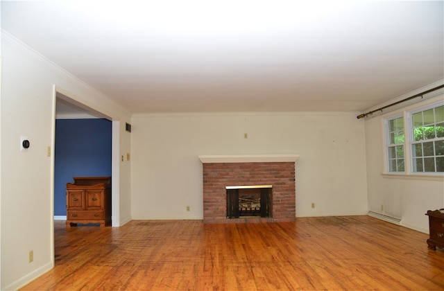 unfurnished living room with a brick fireplace, light wood-type flooring, baseboard heating, and ornamental molding