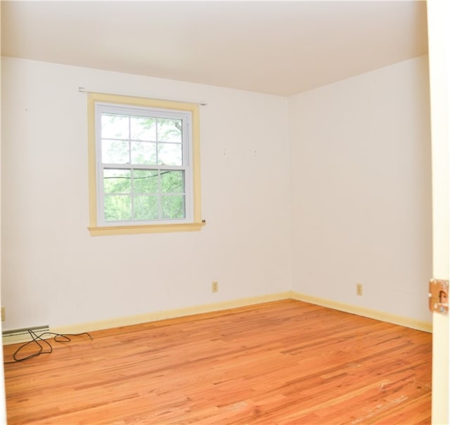 unfurnished room with a baseboard heating unit and light hardwood / wood-style flooring