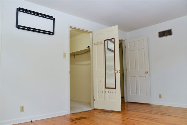 unfurnished bedroom featuring light wood-type flooring, a spacious closet, and a closet