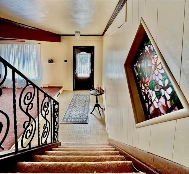 carpeted foyer entrance featuring lofted ceiling, wood walls, and crown molding