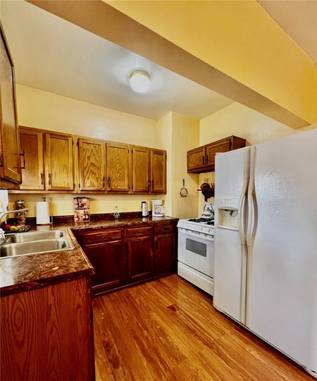 kitchen with wood-type flooring, sink, and white appliances