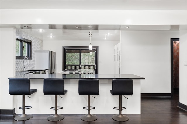 kitchen with decorative light fixtures, backsplash, dark hardwood / wood-style flooring, and a breakfast bar