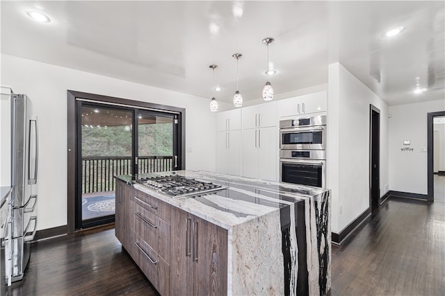 kitchen with white cabinets, a center island, appliances with stainless steel finishes, light stone countertops, and dark hardwood / wood-style floors