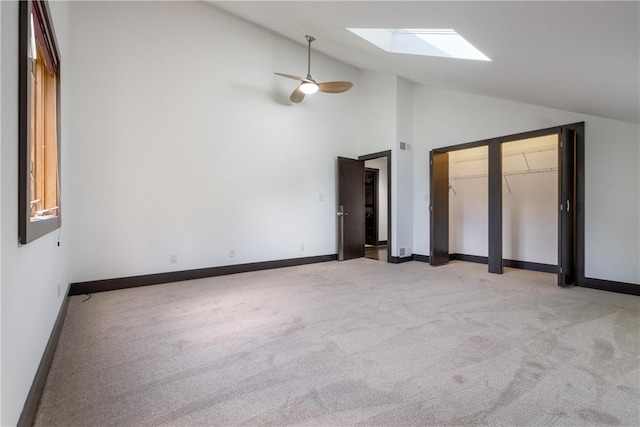 unfurnished bedroom with ceiling fan, light carpet, high vaulted ceiling, and a skylight