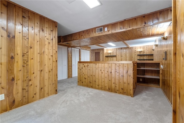 interior space featuring wood walls, kitchen peninsula, and carpet floors