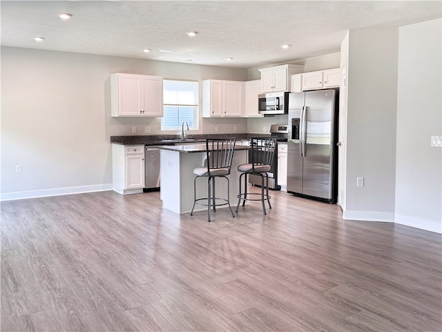 kitchen featuring white cabinetry, hardwood / wood-style flooring, a breakfast bar area, and stainless steel appliances