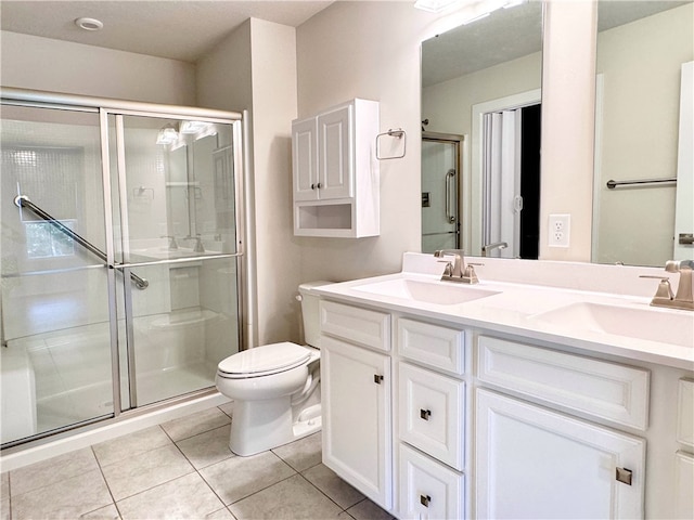 bathroom featuring tile patterned flooring, toilet, a shower with door, and vanity