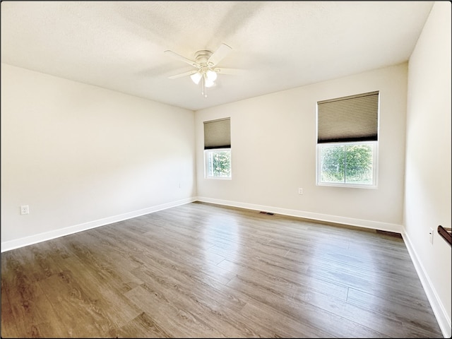 unfurnished room featuring ceiling fan, hardwood / wood-style flooring, a textured ceiling, and a healthy amount of sunlight