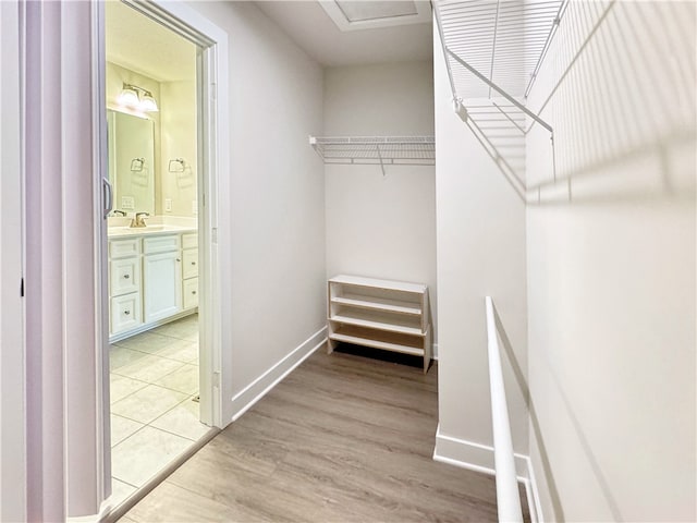 walk in closet with light wood-type flooring and sink