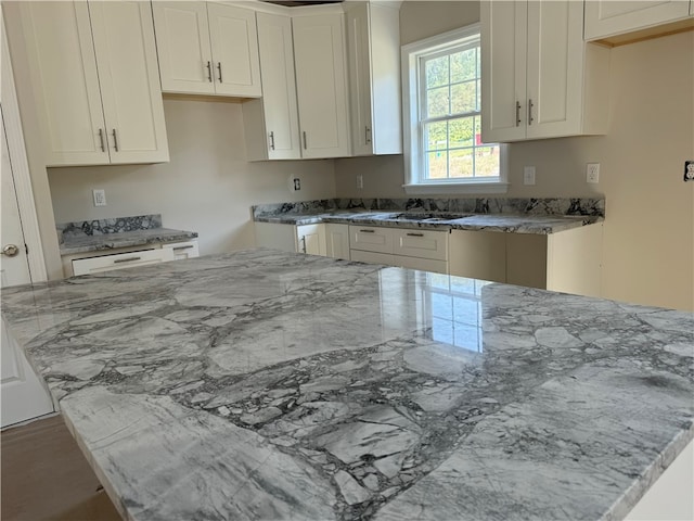 kitchen featuring sink, light stone countertops, and white cabinetry