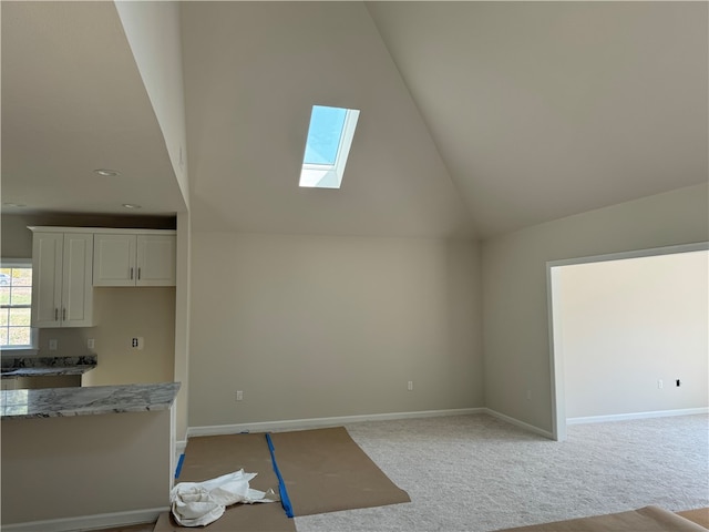 unfurnished living room featuring light carpet, high vaulted ceiling, and a skylight