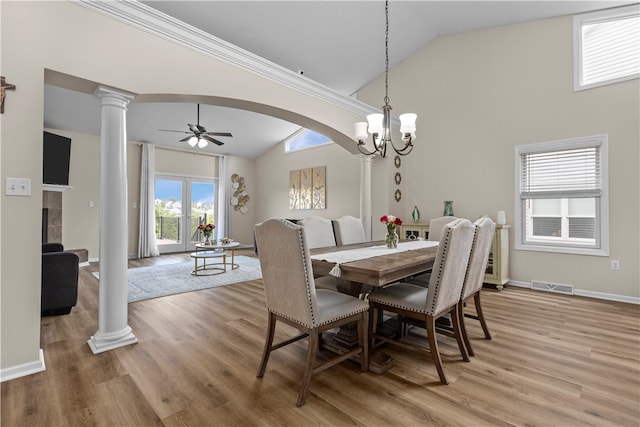 dining space featuring ceiling fan with notable chandelier, high vaulted ceiling, wood-type flooring, and decorative columns