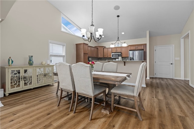 dining room featuring high vaulted ceiling, wood-type flooring, and an inviting chandelier