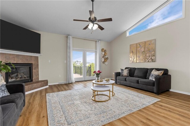 living room featuring a tile fireplace, hardwood / wood-style floors, french doors, high vaulted ceiling, and ceiling fan