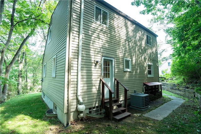 back of property featuring central AC unit and a lawn