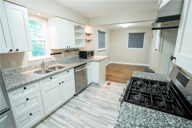 kitchen with light wood-type flooring, light stone counters, stainless steel appliances, white cabinetry, and extractor fan