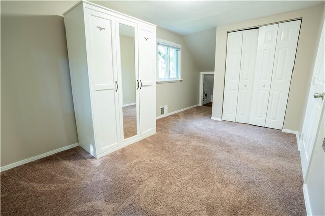 unfurnished bedroom with lofted ceiling, a closet, and carpet floors