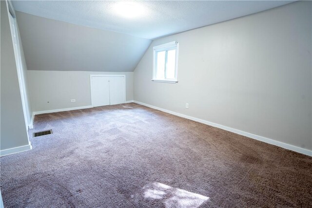 bonus room with vaulted ceiling, a textured ceiling, and carpet floors