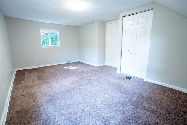 unfurnished bedroom featuring a closet, lofted ceiling, a textured ceiling, and carpet floors