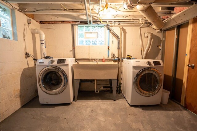 clothes washing area with separate washer and dryer and sink