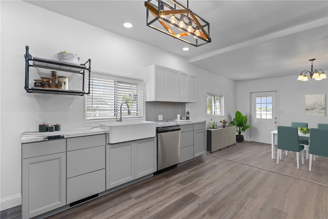 kitchen featuring a wealth of natural light, a notable chandelier, dishwasher, and a sink