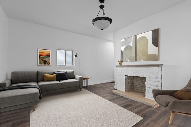 living room with a stone fireplace and dark hardwood / wood-style flooring