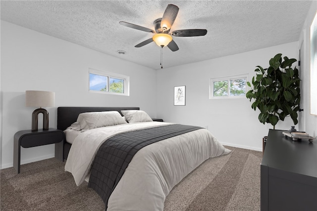 carpeted bedroom with a textured ceiling, ceiling fan, and multiple windows