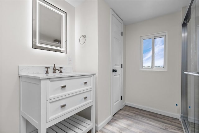 bathroom with baseboards, wood finished floors, and vanity