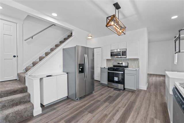 kitchen with appliances with stainless steel finishes, hanging light fixtures, dark wood-type flooring, and white cabinets