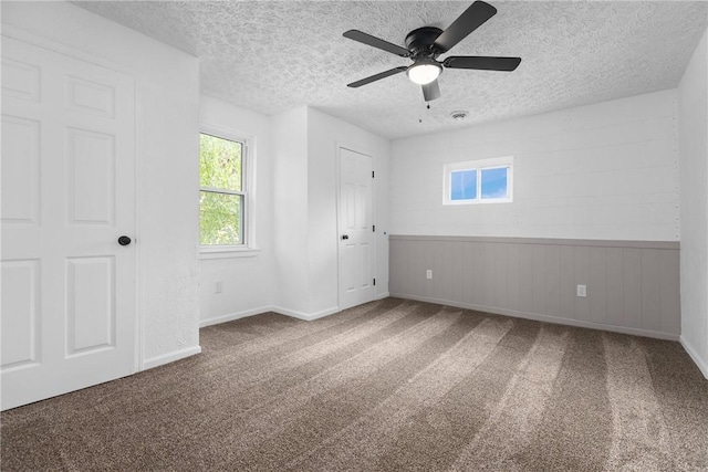 unfurnished room featuring a textured ceiling, carpet floors, and ceiling fan