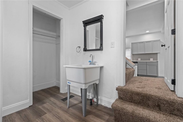 bathroom with visible vents, crown molding, baseboards, and wood finished floors