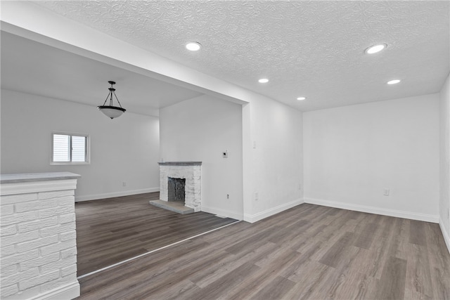 unfurnished living room with a textured ceiling, a fireplace, and hardwood / wood-style floors