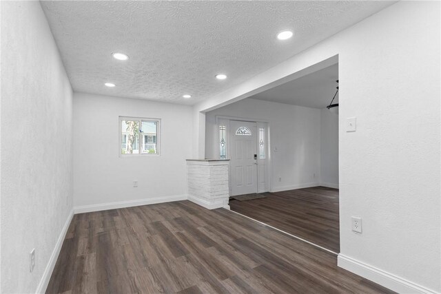 spare room featuring a textured ceiling and dark wood-type flooring