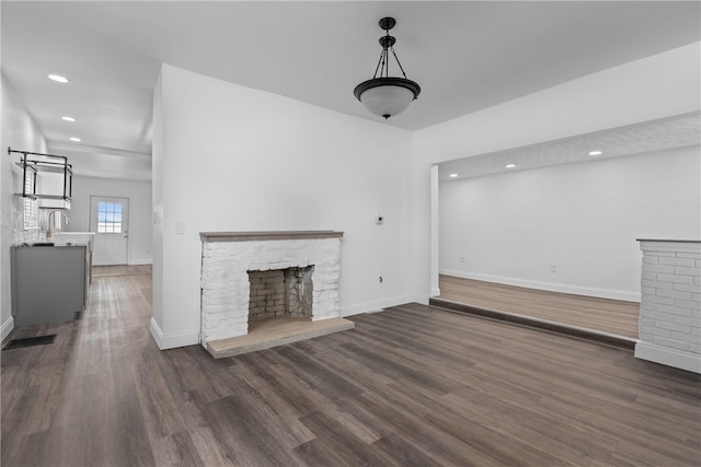 unfurnished living room featuring a fireplace and dark wood-type flooring