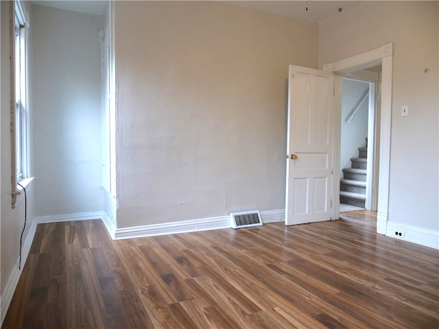 spare room featuring a wealth of natural light and dark hardwood / wood-style flooring