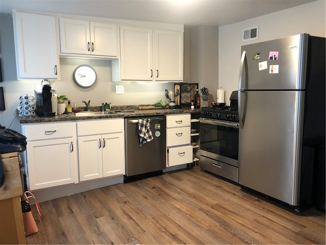 kitchen featuring dark stone counters, sink, dark hardwood / wood-style floors, appliances with stainless steel finishes, and white cabinets