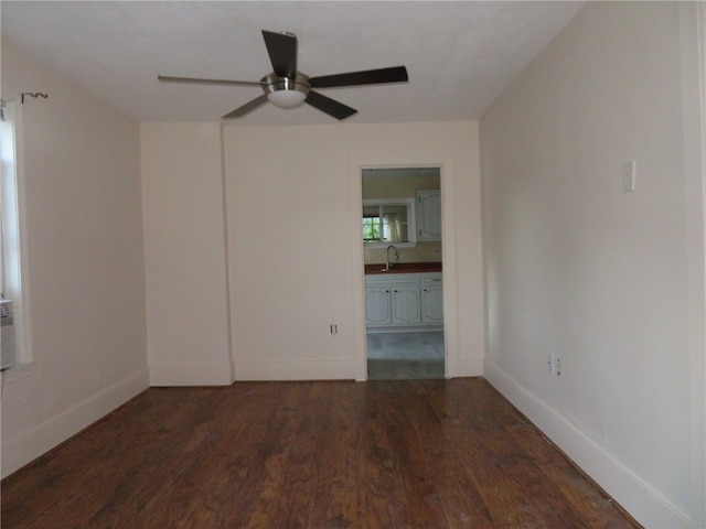 unfurnished room featuring dark hardwood / wood-style flooring, sink, and ceiling fan