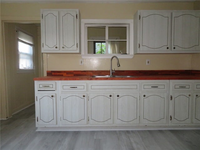 kitchen with a healthy amount of sunlight, wood counters, sink, and light hardwood / wood-style floors