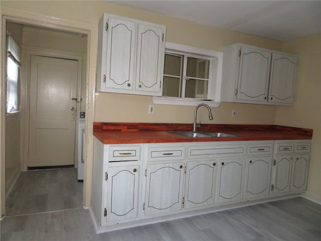 kitchen with hardwood / wood-style floors, white cabinets, and sink