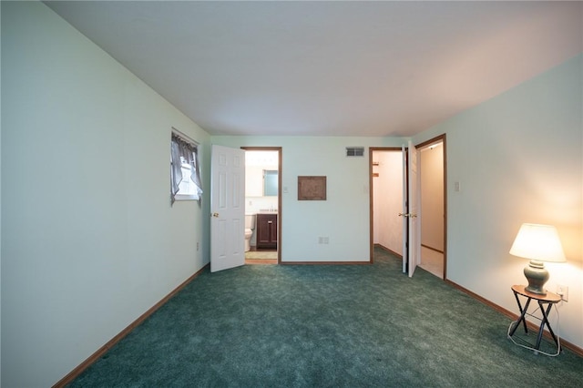 unfurnished bedroom featuring dark colored carpet and ensuite bath