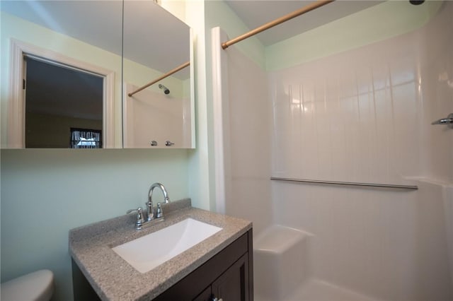 bathroom with a shower, vanity, and toilet