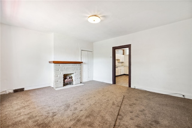 unfurnished living room featuring a brick fireplace and light colored carpet