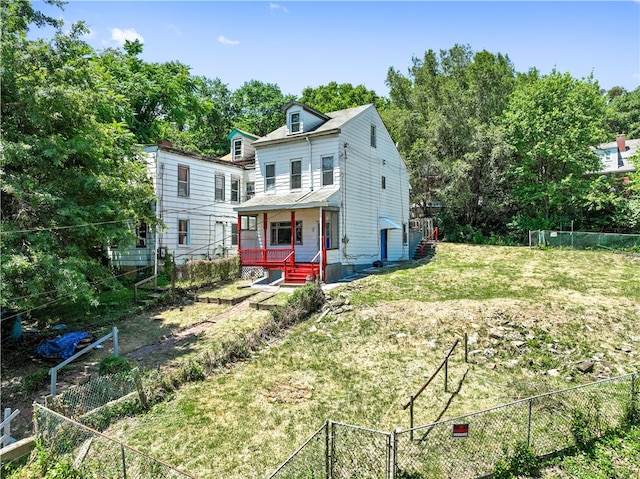 rear view of house featuring a lawn and covered porch