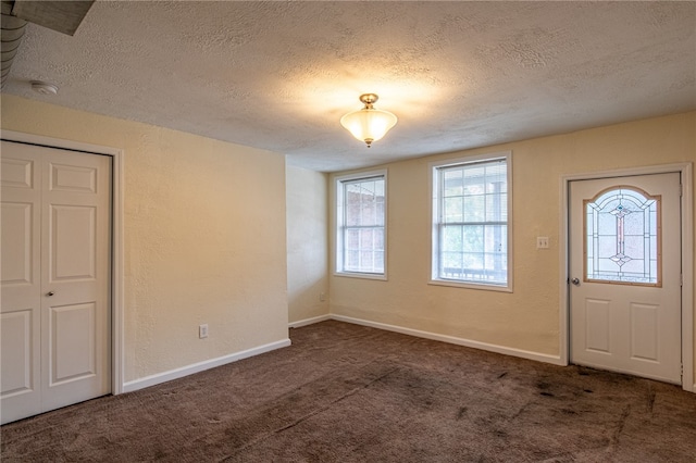 entryway featuring dark carpet and a textured ceiling