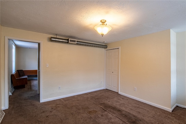 interior space with a textured ceiling and dark colored carpet