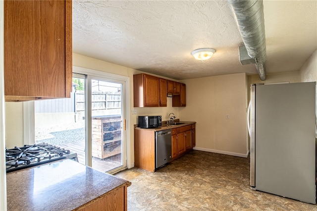 kitchen with a textured ceiling, stainless steel appliances, and sink